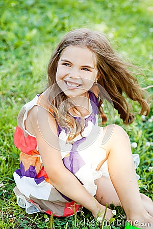 Happy little girl is sitting on the grass Stock Photo