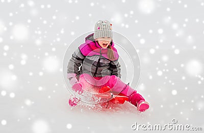 Happy little girl sliding down on sled in winter Stock Photo