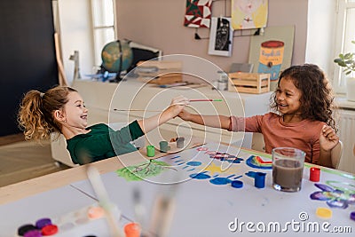 Happy little girls painting picture during creative art and craft class at school. Stock Photo