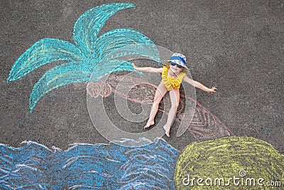 Happy little preschool girl in swimsuit on inflatable ring with sea, sand, palm painted with colorful chalks on asphalt Stock Photo