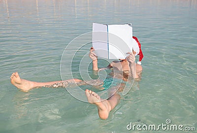 Happy little Santa reading journal at the Dead Sea Stock Photo