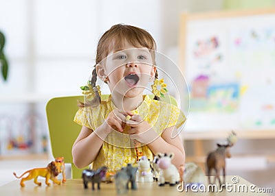 Happy little toddler plays animal toys at home or daycare centre Stock Photo