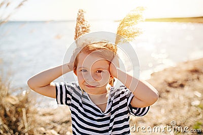 Happy lively little girl with cereal antennas by the lake at spring Stock Photo