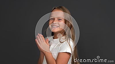 Happy long haired teen girl broadly smiles clapping hands. Nice Caucasian schoolgirl with braces system on teeth Stock Photo