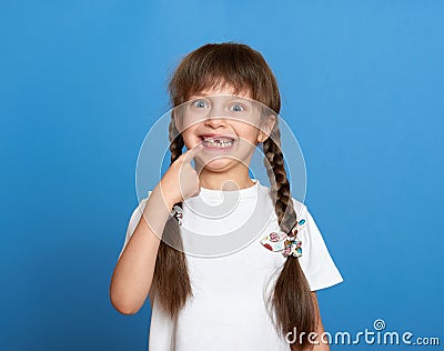 Happy lost tooth girl portrait, studio shoot on blue background Stock Photo