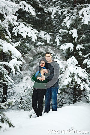 Happy loving couple walking in snowy winter forest, spending christmas vacation together. Lifestyle capture. Stock Photo