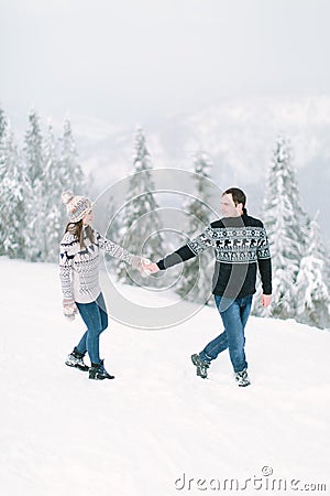 Happy loving couple walking in snowy winter forest, spending christmas vacation together. Outdoor seasonal activities. Lifestyle c Stock Photo