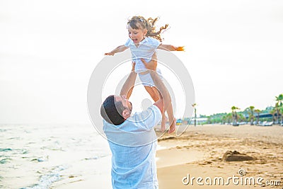 Happy loving father throws up little 3 year old daughter by the sea. People can fly Stock Photo