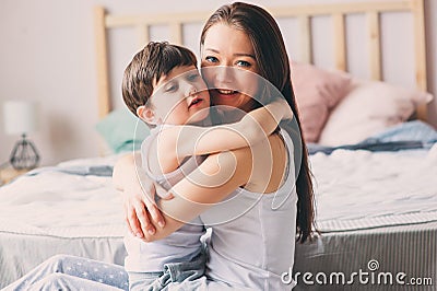 Happy loving mother hugs with child son in the morning in bed Stock Photo