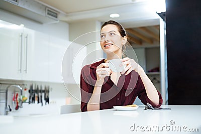 Happy lwoman drinking tea and smiling on the kitchen Stock Photo