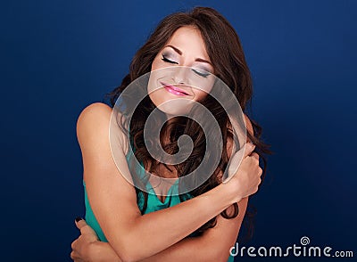 Happy makeup woman hugging herself with natural emotional enjoying face. Love concept of yourself body and face on blue background Stock Photo