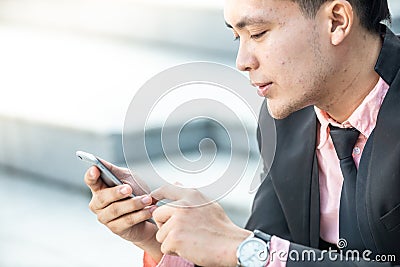 Happy Malay Businessman looking at his smartphone Stock Photo