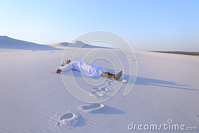 Happy male Arab lies along white sand desert and rejoices in new Stock Photo