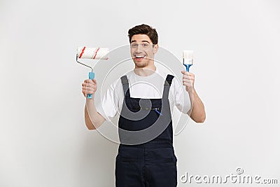 Happy male builder holding paint roll and brush Stock Photo