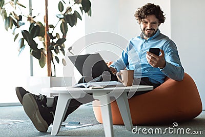 Portrait of smiling man using smartphone and pc at office Stock Photo
