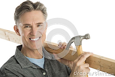 Happy Male Carpenter Holding Hammer And Plank Stock Photo