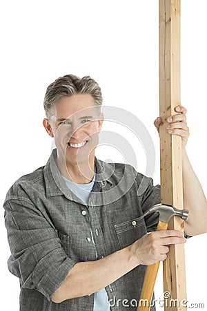 Happy Male Carpenter Holding Hammer And Wooden Plank Stock Photo