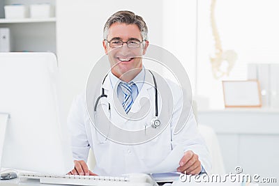 Happy male doctor reviewing documents at table Stock Photo