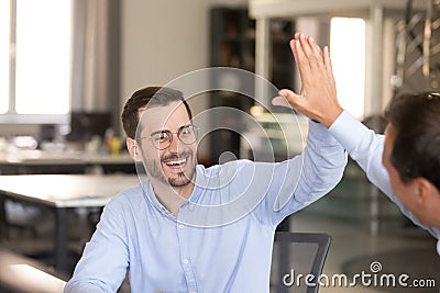 Happy male employee giving high five to colleague Stock Photo