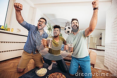 Male friends supporting football team at home Stock Photo