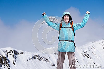 Happy male mountaineer man with raised arms. In background high mountains above clouds . Stock Photo