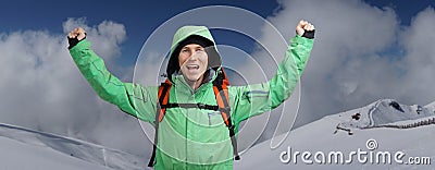 Happy male mountaineer man with raised arms. In background high mountains above clouds . Stock Photo