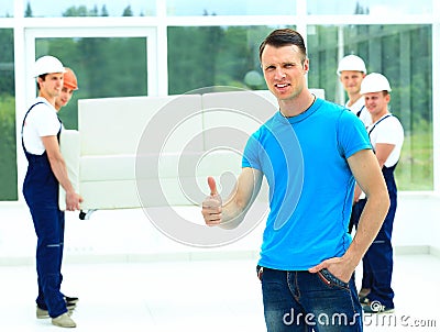 Happy male movers in uniform carrying Stock Photo