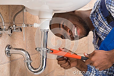 Happy Male Plumber Repairing Sink In Bathroom Stock Photo