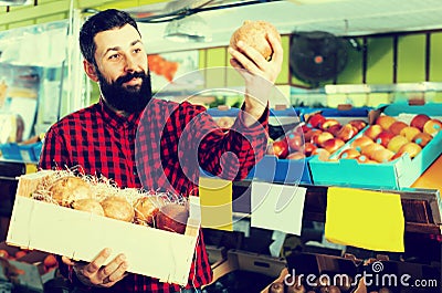 Happy male seller offering pomegranates in shop Stock Photo