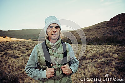 Happy male teen hiking in luscious mountain dressed warmly reading to exercise Stock Photo