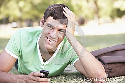 Happy Male Teenage Student With Mobile Phone In Park Stock Photo