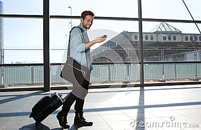 Happy male traveler walking with bags and cellphone Stock Photo