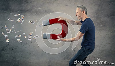 Happy man with a big magnet attracting money Stock Photo