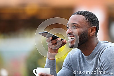 Happy man with black skin dictating message on phone Stock Photo