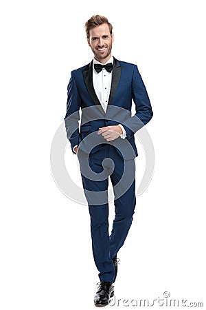 Happy man in blue tuxedo walking with hand in pocket Stock Photo