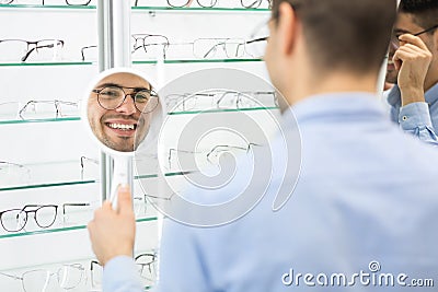 Happy man choosing glasses at optics store Stock Photo