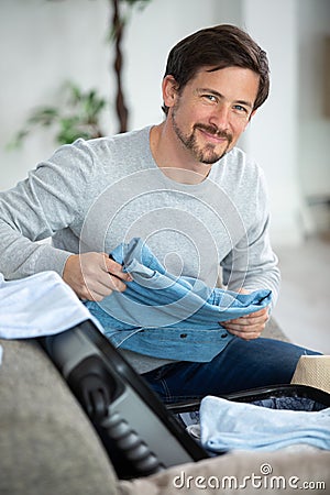 happy man on couch preparing travel back and packing suitcase Stock Photo