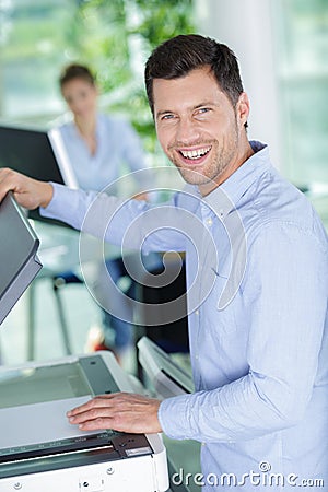 Happy man doing documents copies on copying machine Stock Photo