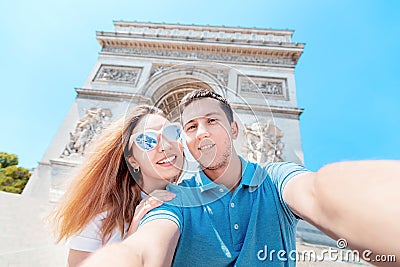 Man and a girl hug and take a selfie photo against the Arc de Triomphe in Paris. Honeymoon and a trip together in France Stock Photo