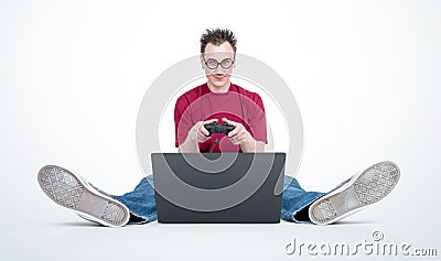 Happy man in glasses with joystick sitting on the floor in front of a laptop Stock Photo