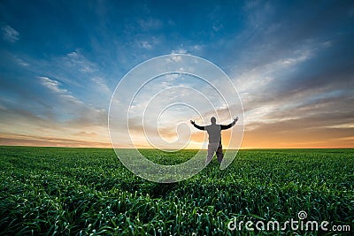 Happy man on green field of wheat at sunrise Stock Photo