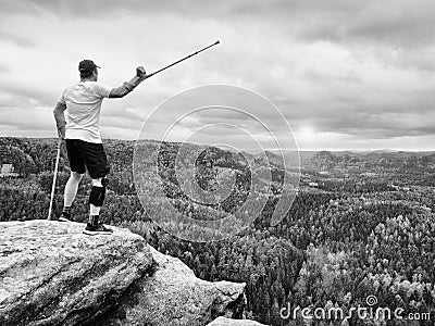 Happy man hiker holding medicine crutch above head, injured knee fixed in knee brace feature Stock Photo