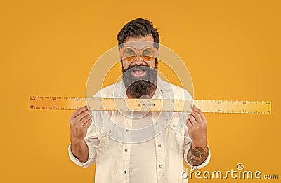 happy man hold geometry ruler isolated on yellow. man hold geometry ruler in studio. Stock Photo