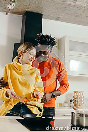 Happy man hugging his girlfriend while cooking with her Stock Photo