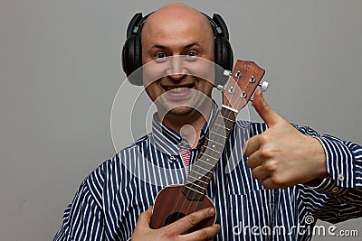 Happy man palying ukulele guitar with headphones Stock Photo