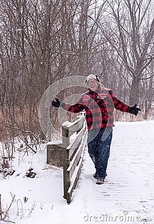 Happy man walking across a wooden bridge in the snow Stock Photo