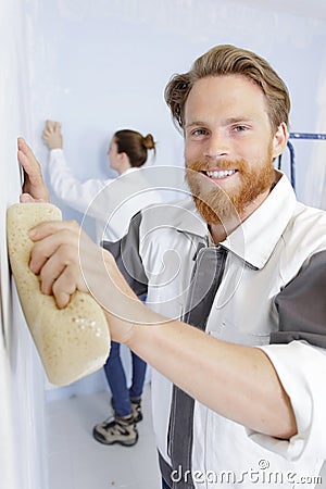 happy man polishing plastered walls with sponge Stock Photo