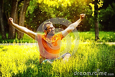 A happy man is relaxing on green grass with squint eyes Stock Photo