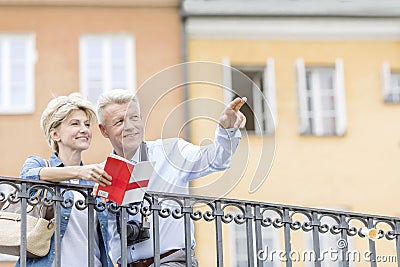 Happy man showing something to woman with guidebook in city Stock Photo