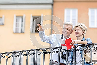 Happy man showing something to woman with guidebook in city Stock Photo